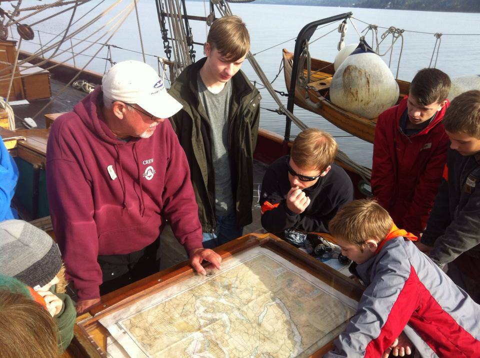 People gathered around a map while on the deck of a boat